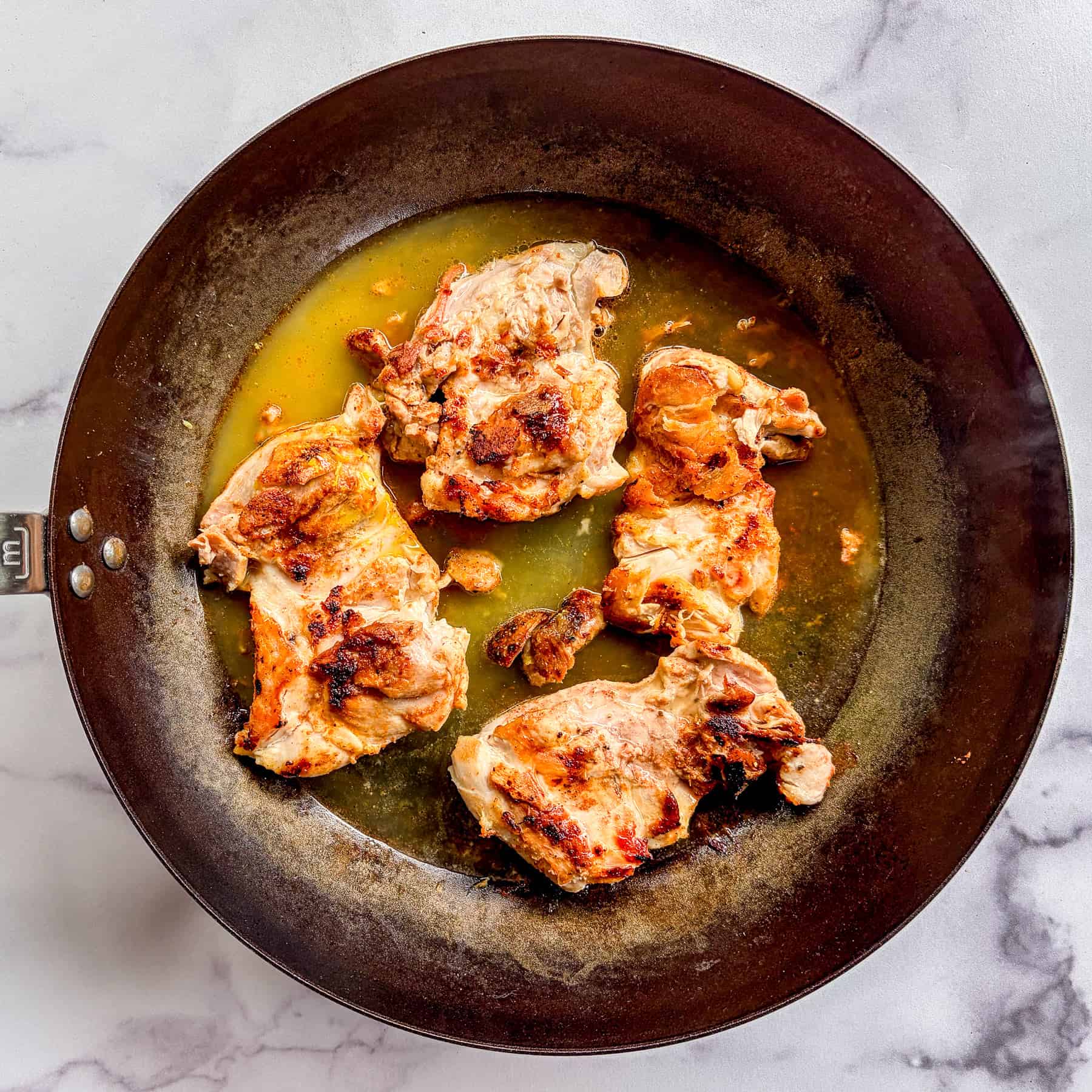 Chicken thighs cooking in stock.