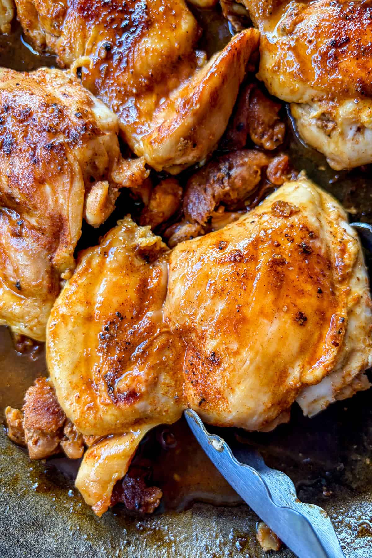 Cooked chicken thighs in a skillet.
