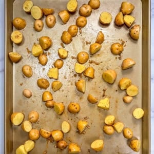 Halved baby potatoes on a sheet pan.