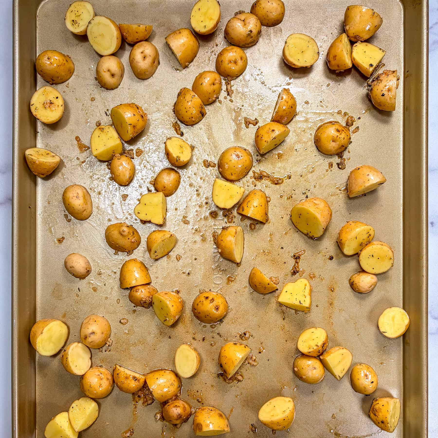 Halved baby potatoes on a sheet pan.