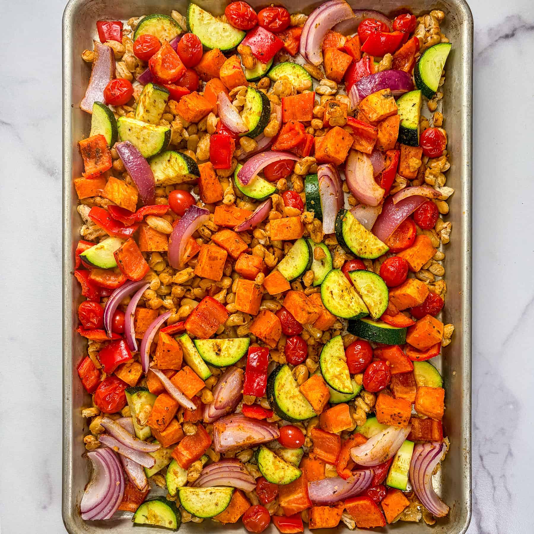 Vegetables and white beans on a sheet pan.