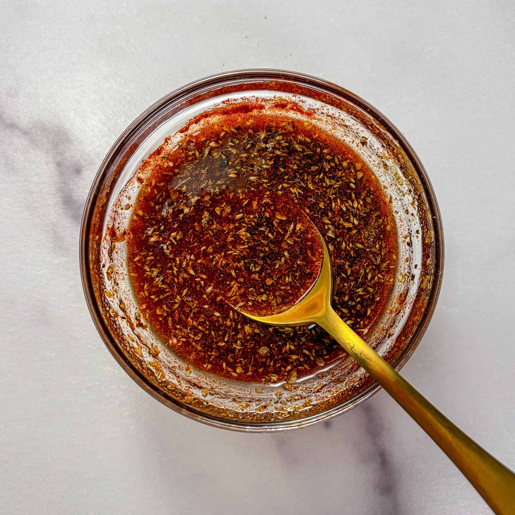 Sauce for Mediterranean white beans and veggies in a glass bowl.