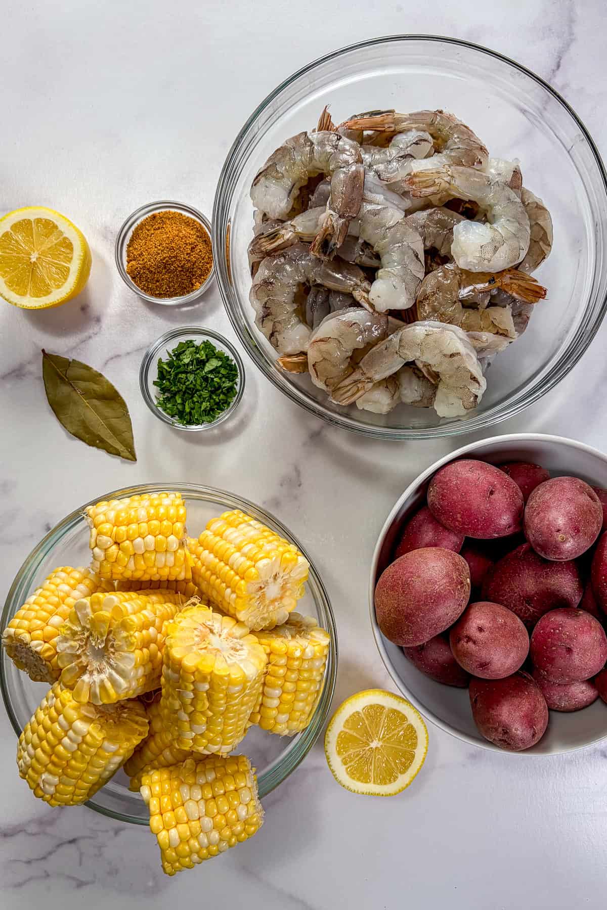Shrimp seafood boil ingredients on a marble background.