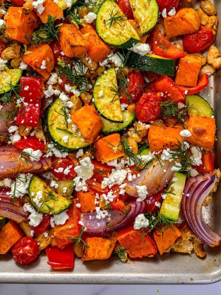 Sheet pan roasted vegetables and white beans topped with feta and dill.